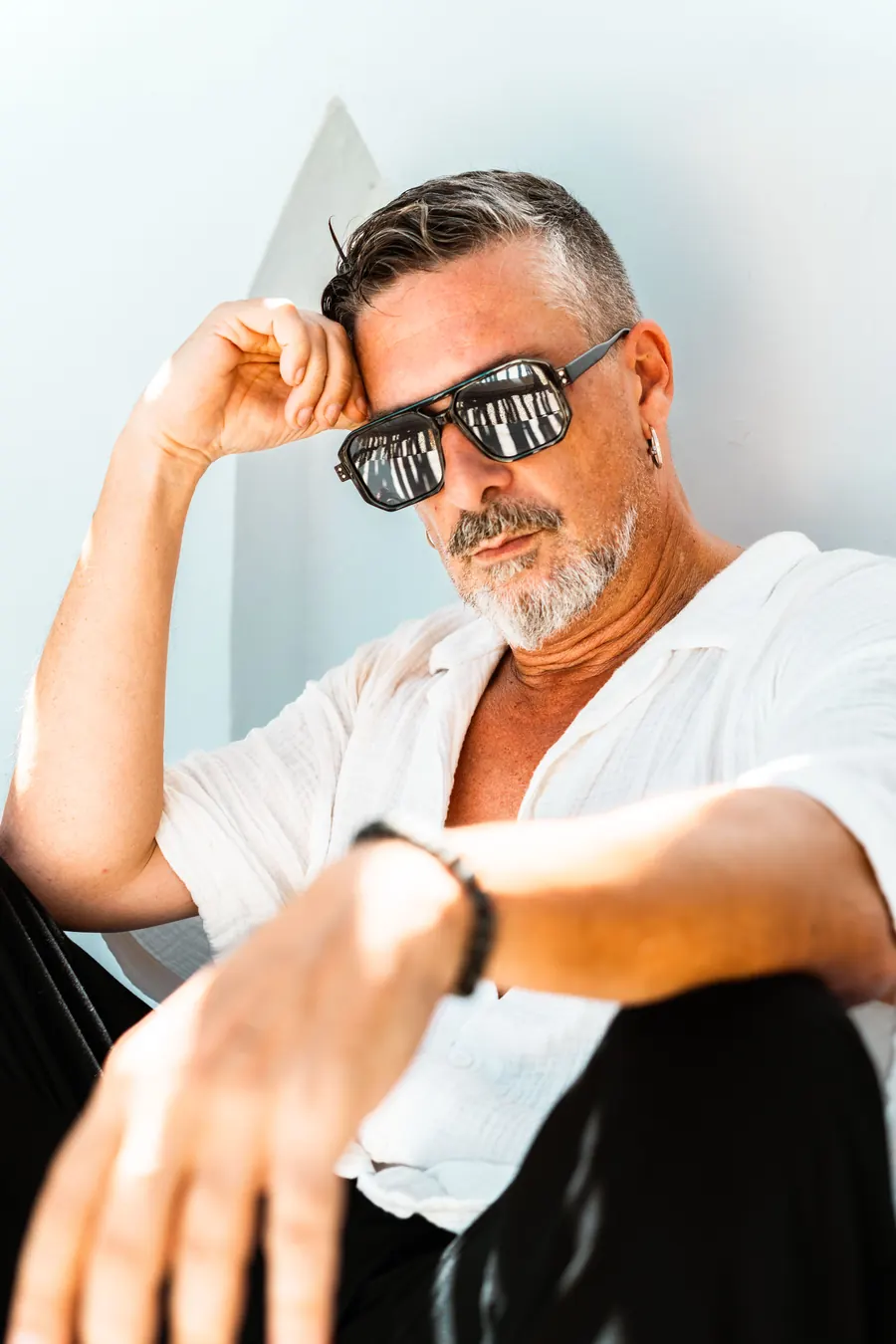 DJ INO leaning on a white wall